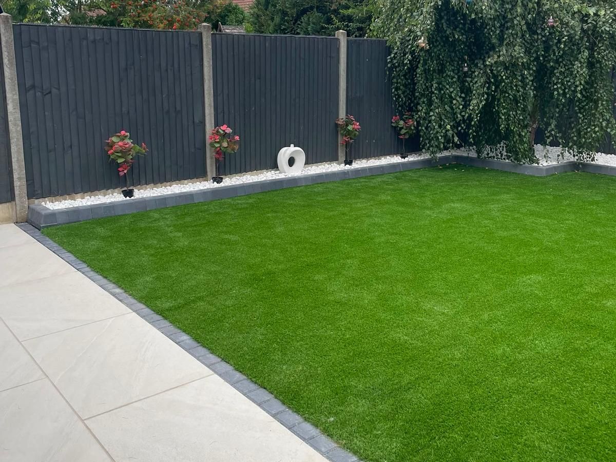 Artificial grass laid to a stone border with grey slatted fencing