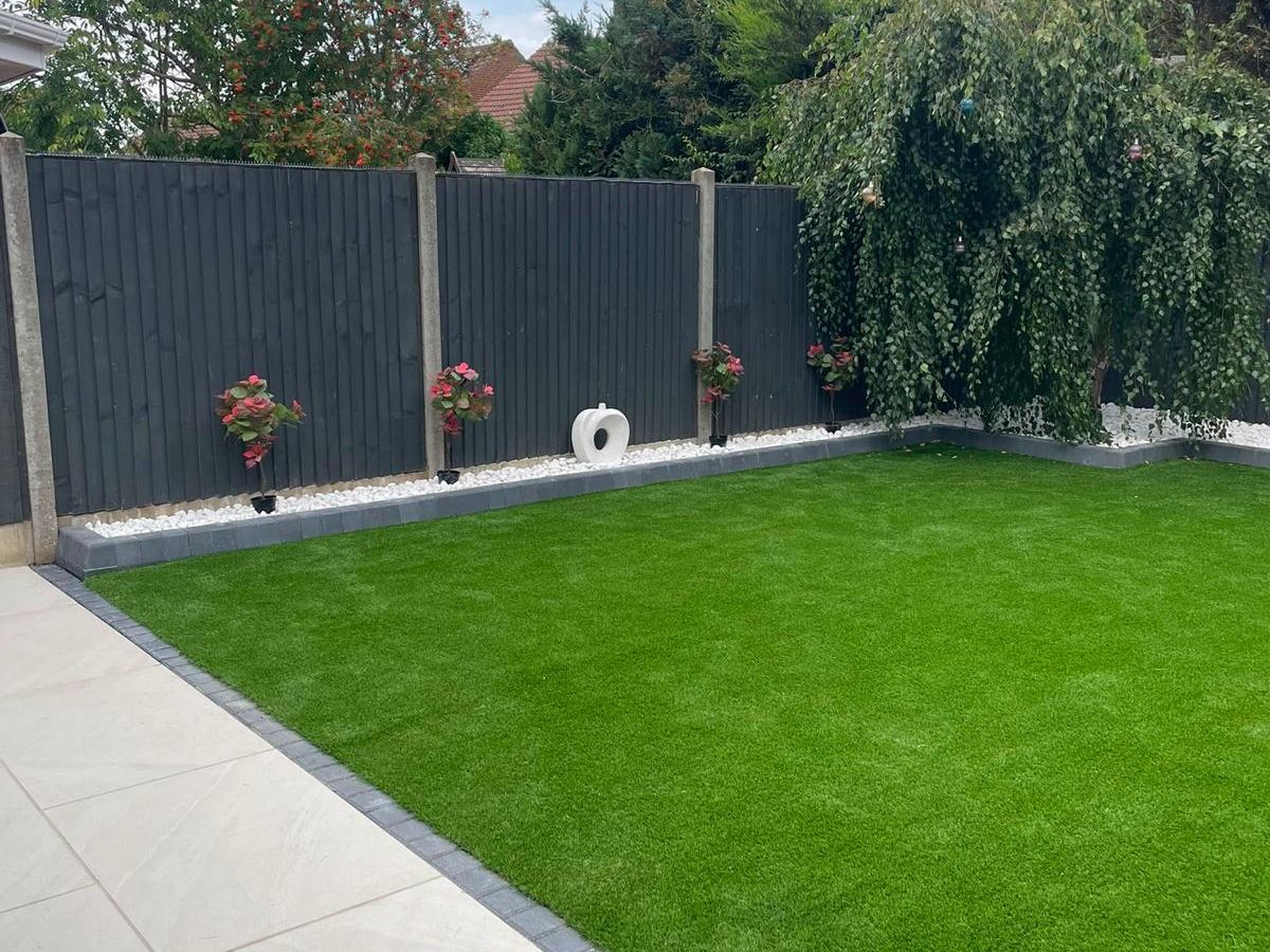 Artificial grass laid to a stone border with grey slatted fencing