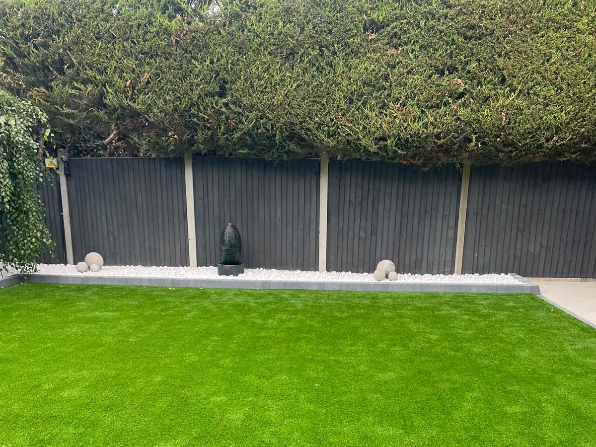 A fence run above a gravel border with planted pots