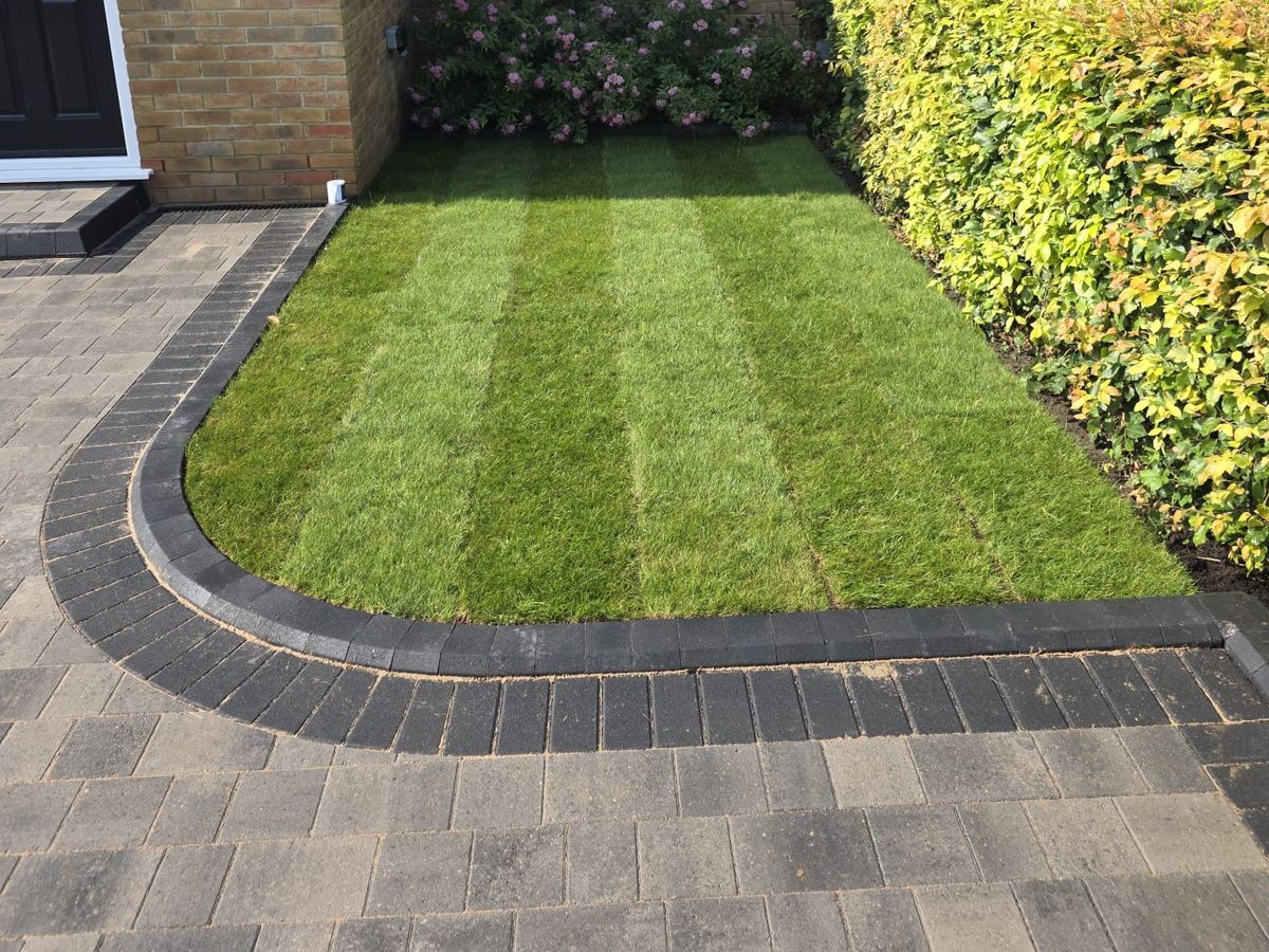 A new lawn edged with a curved charcoal block paving border