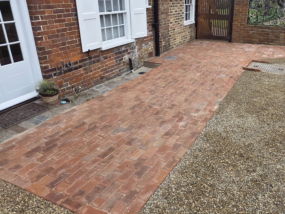 A clay paver driveway and gravel forecourt in front of a period brick cottage