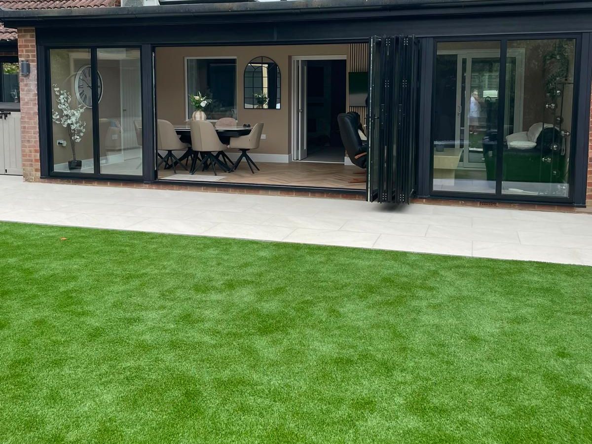 Artificial lawn and porcelain paving outside a house with bi-fold doors