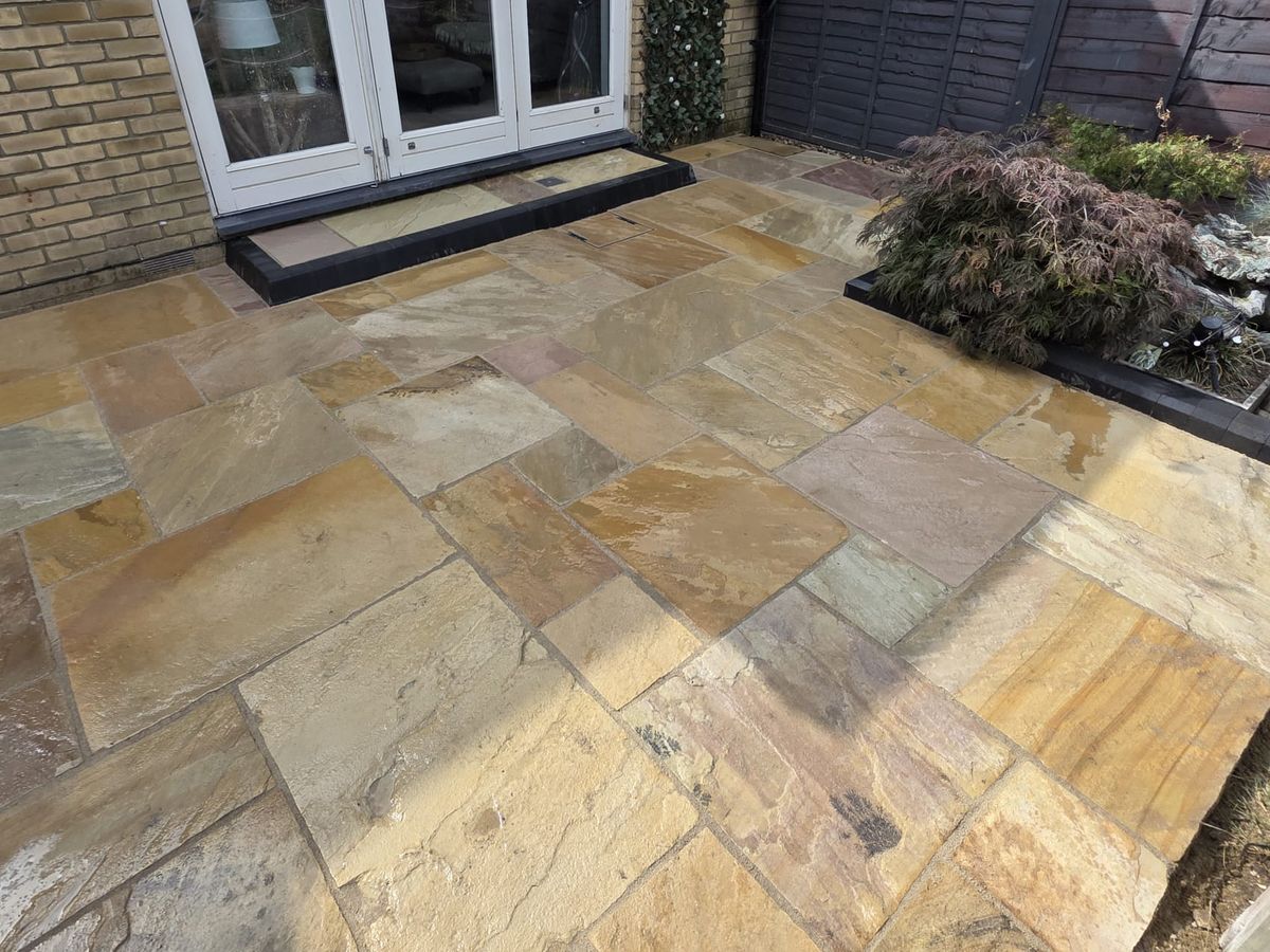 Indian sandstone paving laid in mixed tones against a garden border