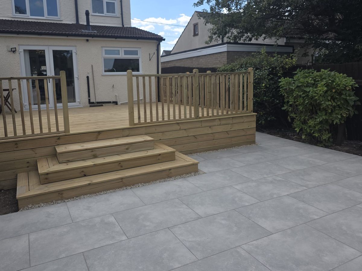 A porcelain paved patio with timber deck steps leading down from the house