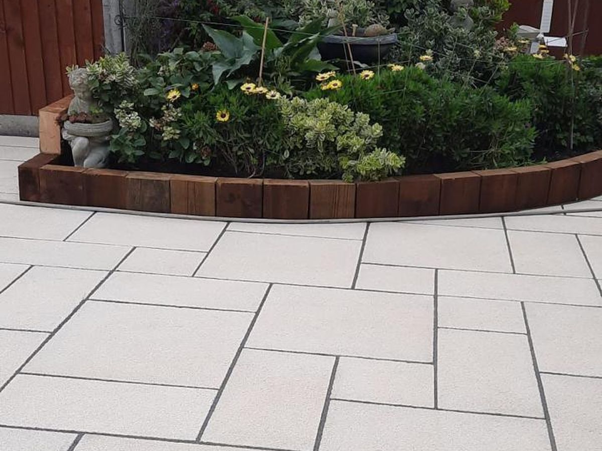 New paving meeting a curved timber sleeper planter and planted border