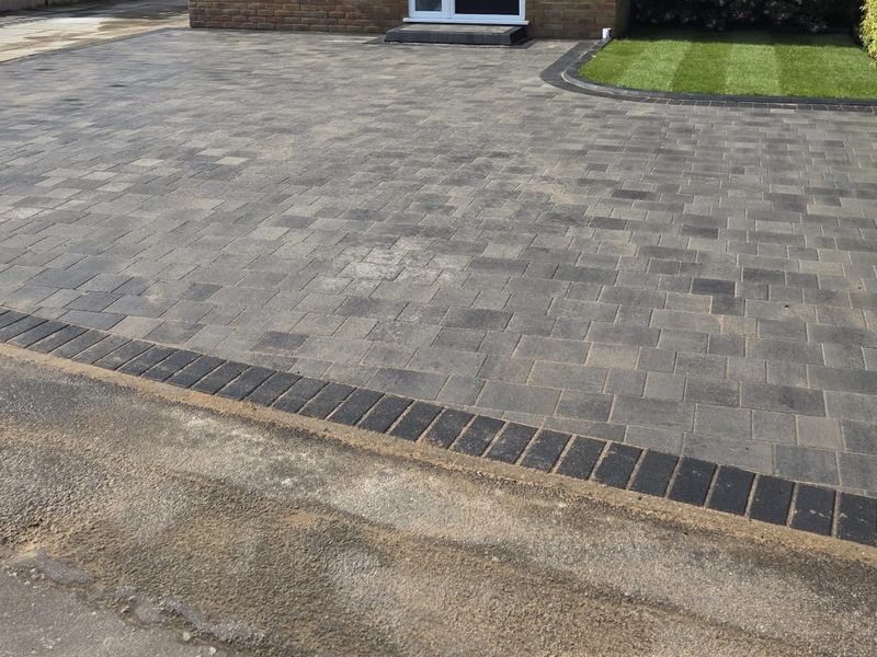 A block paved driveway in grey and charcoal with a contrasting border course