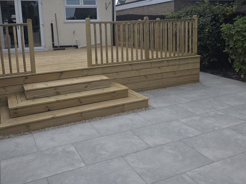Timber deck steps and balustrade leading down to a porcelain paved patio