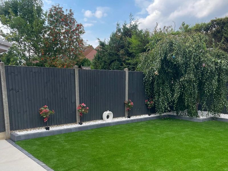 Grey slatted panel fencing above a stone border