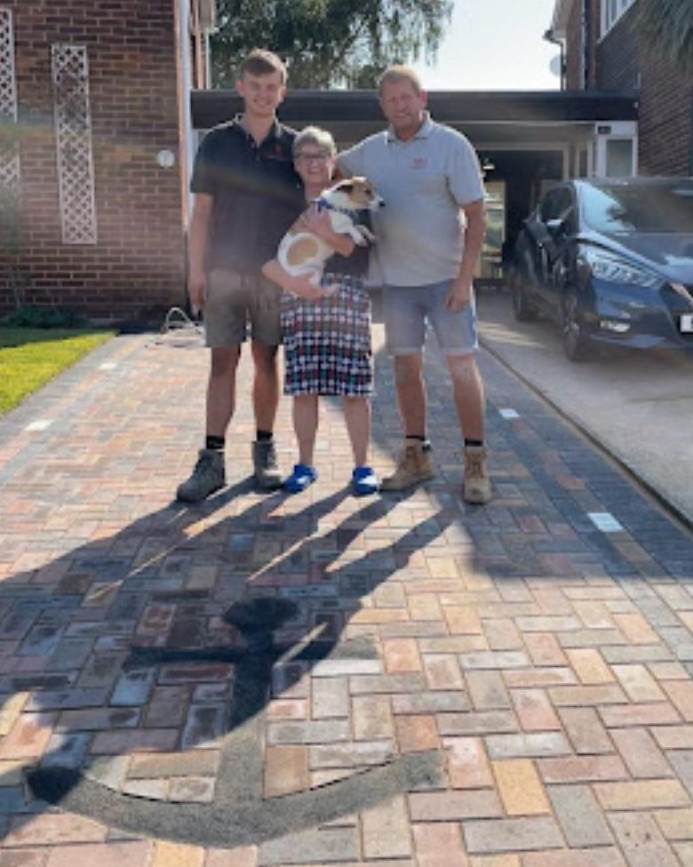 Dave, Joe and a customer with her dog on a block paved driveway
